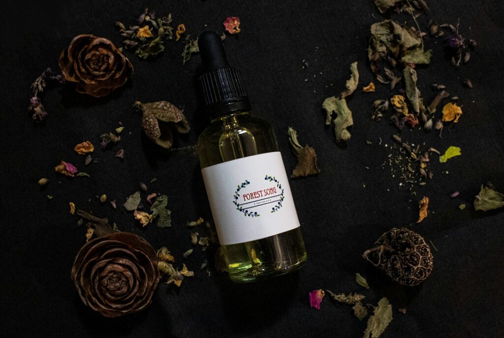 a bottle of essential oil surrounded by dried flowers